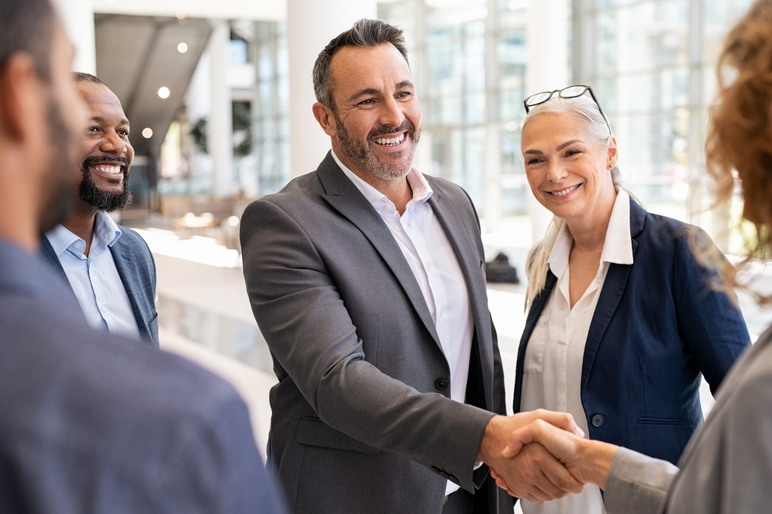 Business professionals shake hands after a meeting, building trust to help retain customers.